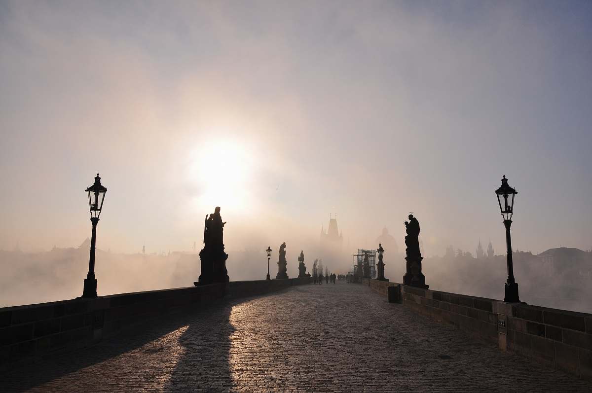 st.charles bridge concrete pathway with light post under white sky czechia